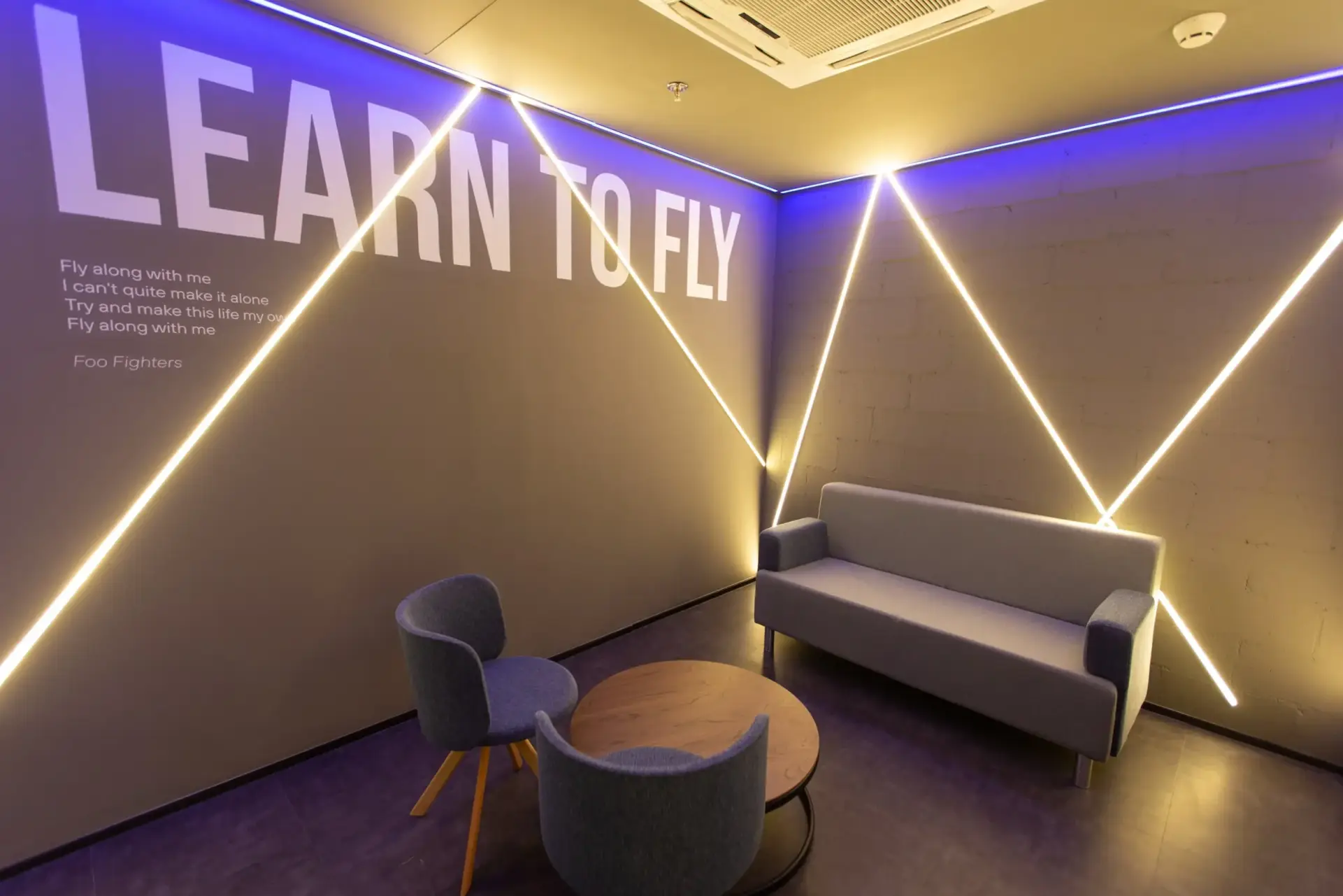 Sala de trabalho, onde uma parede possui trecho da música “Learn to Fly” do Foo Fighters