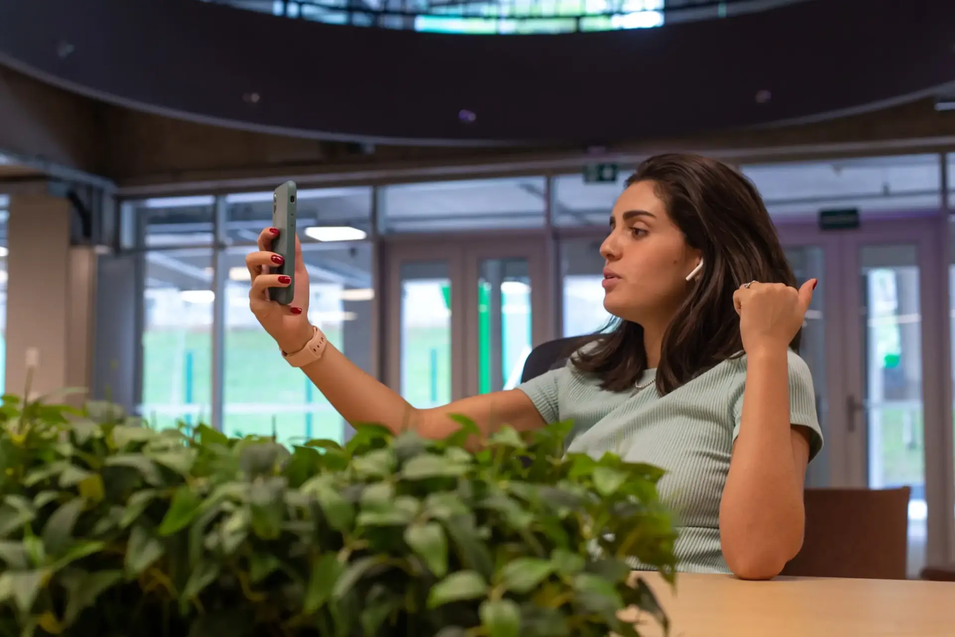 Mulher usando fones de ouvido e tirando uma selfie no Base Coworking.